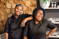 Portrait of two stylists standing together in beauty salon looking at camera and smiling