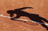 FILE - A tennis player casts a shadow on the clay court of the French Open tennis tournament at the Roland Garros stadium in Paris, Sunday, June 2, 2019. The women’s professional tennis tour has launched a commercial enterprise with CVC Capital Partners to increase revenues for the sport. The global investment manager is contributing $150 million for a 20% stake in what will be known as WTA Ventures LLC. WTA Chairman and CEO Steve Simon said the goal is to grow the profile, value and prize money of women’s professional tennis. (AP Photo/Christophe Ena, File)