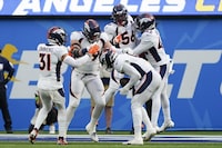 Denver Broncos linebacker Jonathon Cooper (0) celebrates with teammates after intercepting a pass batted by linebacker Baron Browning (56) during the first half of an NFL football game against the Los Angeles Chargers, Sunday, Dec. 10, 2023, in Inglewood, Calif. (AP Photo/Ryan Sun)