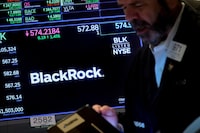 A trader works as a screen displays the trading information for BlackRock on the floor of the New York Stock Exchange (NYSE) on Oct. 14, 2022.