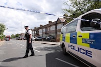 A police officer stands on duty at a cordon of a crime scene in Hainault, east of London on April 30, 2024, where a 36-year-old man wielding a sword was arrested following an attack on members of the public and two police officers. A 13-year-old boy died on Tuesday after five people, including two police officers, were wounded by a man wielding a sword in east London, police said. "It's with great sadness that one of those injured in this incident, a 13-year-old boy, has died from their injuries," Chief Superintendent Stuart Bell, from the Metropolitan Police, told reporters. (Photo by Adrian DENNIS / AFP) (Photo by ADRIAN DENNIS/AFP via Getty Images)
