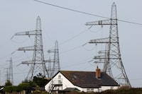 FILE PHOTO: Electricity pylons are seen behind a local house in Dungeness, Britain, October 8, 2023. REUTERS/Carlos Jasso/File Photo