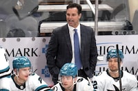 FILE - San Jose Sharks head coach David Quinn, center top, stands behind his bench during the third period of an NHL hockey game against the Pittsburgh Penguins in Pittsburgh, Thursday, March 14, 2024. The San Jose Sharks have fired coach David Quinn after two rough seasons as part of a massive rebuilding project. General manager Mike Grier announced the decision on Wednesday, April 24, following a review of the team's season. (AP Photo/Gene J. Puskar, File)