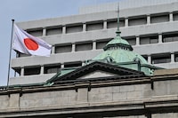 The Japanese flag flies over part of the Bank of Japan (BoJ) headquarters complex in central Tokyo on March 19, 2024. Japan's central bank was widely expected later on March 19 to scrap its maverick negative interest rate policy and hike borrowing costs for the first time in 17 years, according to economists and media reports. (Photo by Richard A. Brooks / AFP) (Photo by RICHARD A. BROOKS/AFP via Getty Images)