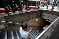 A TTC user checking their phone while heading down to the subway station at College St. is photographed on Aug 21, 2023. (Fred Lum/The Globe and Mail)