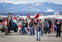 Anti-carbon tax protesters wave signs and chant slogans as they block a westbound lane of the Trans Canada highway near Cochrane, Alta., Monday, April 1, 2024. Mounties in Alberta say they’re keeping traffic moving on the Trans-Canada Highway despite a roadside carbon-levy protest, and say five large farm tractors have already caused a multi-vehicle crash. THE CANADIAN PRESS/Jeff McIntosh