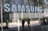 (FILES) People walk past the Samsung logo displayed on a glass door at the company's Seocho building in Seoul on April 5, 2024. The United States on April 15, 2024, announced grants of up to $6.4 billion to South Korean semiconductor giant Samsung to produce cutting-edge chips in Texas. (Photo by Jung Yeon-je / AFP) (Photo by JUNG YEON-JE/AFP via Getty Images)