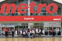 Customers, workers and security stand outside a Metro grocery store in Toronto, Saturday, July 29, 2023. THE CANADIAN PRESS/Cole Burston