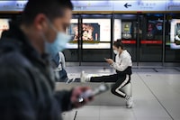 A woman (R) wearing a face mask uses her mobile phone at a subway station in Beijing on April 11, 2020, amid the COVID-19 coronavirus pandemic. (Photo by WANG ZHAO / AFP) (Photo by WANG ZHAO/AFP via Getty Images)