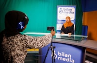 Shukri Mohamed Abdi and Fathi Mohamed Ahmed, journalists at Bilan Media, Somalia's first all-women media team, use a mobile to record the news inside the Bilan Media studios in Mogadishu, Somalia August 20, 2023. REUTERS/Feisal Omar