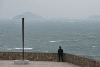A man looks out over stormy seas in the Taiwan Strait, from Pingtan Island, the closest point in China to Taiwan's main island, in China's southeast Fujian province on January 15, 2024. (Photo by GREG BAKER / AFP) (Photo by GREG BAKER/AFP via Getty Images)