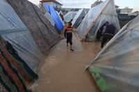 A displaced Palestinian boy walks amid tents flooded by heavy rain, at a makeshift camp set up by people who fled the ongoing battles between Israel and Hamas militants, in Rafah in the southern Gaza Strip on January 27, 2024. (Photo by AFP) (Photo by -/AFP via Getty Images)