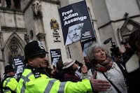 Police officers stand guard as supporters of WikiLeaks founder Julian Assange hold placards outside The Royal Courts of Justice, Britain's High Court, in central London on March 26, 2024. Two UK judges delayed a decision on whether to grant Assange a last-ditch appeal against extradition to the United States, giving Washington three weeks to provide "assurances" in the case. (Photo by Daniel LEAL / AFP) (Photo by DANIEL LEAL/AFP via Getty Images)
