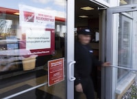 A man walks past a sign looking for full and part-time employees and a sign asking for patience at a Tim Hortons in St-Bruno-de-Montarville, Quebec, September 29, 2022.   (Christinne Muschi /The Globe and Mail)