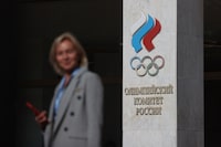 A woman stands next to a logo of Russia's Olympic Committee before a plenary session of the extended meeting of the ROC athletes' commission in Moscow on September 14, 2023. (Photo by AFP) (Photo by -/AFP via Getty Images)