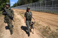 A member of Lithuanian Riflemen's Union and a Border Guard officer patrol along Belarus border in Kaniukai, Lithuania July 7, 2023. REUTERS/Janis Laizans