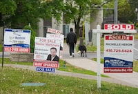 A person walks past multiple for-sale and sold real estate signs in Mississauga, Ont., on Wednesday, May 24, 2023. People renewing their mortgages or looking to buy a home are faced with a very different decision than they might have been just a few years ago, experts said, as rapid interest-rate increases have made fixed-rate mortgages with shorter terms more popular while variable-rate mortgage holders feel the pinch. THE CANADIAN PRESS/Nathan Denette