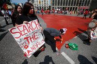 Family and supporters paint a red dress as they gather to protest all levels of governments' lack of action in funding a search of WinnipegÕs landfills for missing women at Portage and Main in Winnipeg, Thursday, August 3, 2023.   THE CANADIAN PRESS/John Woods