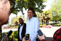 Premier David Eby and BC NDP candidate Ravi Parmar answer questions from the media after their walk along Goldstream Ave. as they visit shops and talk to locals while out in Langford, B.C., on Thursday, May 25, 2023. THE CANADIAN PRESS/Chad Hipolito 
