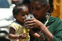 A mother helps her daughter to drink water during a hot summer day in Amritsar on April 25, 2024. (Photo by Narinder NANU / AFP) (Photo by NARINDER NANU/AFP via Getty Images)