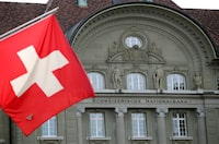FILE PHOTO: A Swiss flag is pictured in front of the Swiss National Bank (SNB) in Bern, Switzerland May 2, 2019. REUTERS/Denis Balibouse//File Photo