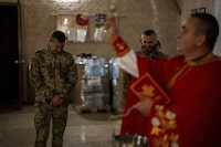 Priest Ivan, blesses Ukrainian servicemen of the 72nd Separate Mechanized Brigade, during a Christian Orthodox Easter religious service Donetsk region, Ukraine, early Sunday, May 5, 2024. (AP Photo/Francisco Seco)