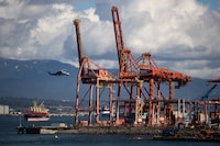A Helijet helicopter flies past gantry cranes at the Port of Vancouver while landing on the harbour in Vancouver, on Wednesday, March 11, 2020. Darryl Dyck/The Globe and Mail