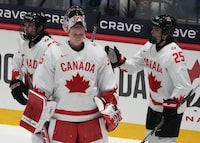 Canada goaltender Ann-Renee Desbiens (35) is consoled by teammates Jaime Bourbonnais (25) and Erin Ambrose (23) following their overtime loss to the United States  at the IIHF Women's World Hockey Championship in Utica, N.Y., Monday, April 8, 2024. THE CANADIAN PRESS/Christinne Muschi