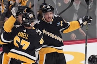 Pittsburgh Penguins' Sidney Crosby (87) celebrates with Kris Letang, rear, and Rickard Rakell (67) after scoring against the Carolina Hurricanes during the first period of an NHL hockey game in Pittsburgh, Thursday, Dec. 21, 2023. (AP Photo/Gene J. Puskar)