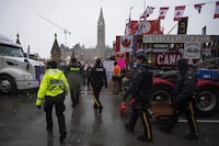 Police walk through parked trucks to make an arrest on Wellington Street, on the 21st day of a protest, in Ottawa, on Thursday, Feb. 17, 2022. The Federal Court ruled Tuesday the Liberal government’s invocation of the Emergencies Act in response to the "Freedom Convoy" protests was unreasonable and led to the infringement of constitutional rights. THE CANADIAN PRESS/Justin Tang