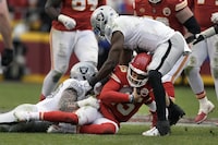 Kansas City Chiefs quarterback Patrick Mahomes (15) is stopped by Las Vegas Raiders defensive end Maxx Crosby (98) and linebacker Divine Deablo (5) during the second half of an NFL football game Monday, Dec. 25, 2023, in Kansas City, Mo. (AP Photo/Charlie Riedel)