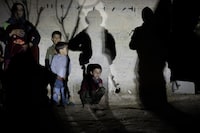 Family of Mahmoud Al-Said, who was accused of being an ISIS operative, stands next to a wall during a night raid in a village in Deir ez-Zor region, April 15, 2023.