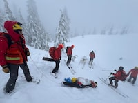 North Shore Rescue workers move a woman to safety along a trail near Pump Peak, in North Vancouver, B.C., in a Sunday, March 10, 2024, handout photo published to social media website Facebook. Rescuers say the woman is lucky to be alive after being caught in an avalanche on Metro Vancouver's North Shore and being completely buried upside down for up to 20 minutes. THE CANADIAN PRESS/HO-North Shore Rescue, *MANDATORY CREDIT*