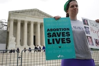 An abortion rights supporter holds placards on the day the Supreme Court justices hear oral arguments over the legality of Idaho's Republican-backed, near-total abortion ban in medical-emergency situations, at the U.S. Supreme Court in Washington, U.S., April 24, 2024. REUTERS/Kevin Lamarque