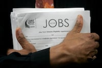 FILE PHOTO: A man carrying a stack of job listings listens to a discussion at the One Stop employment center in San Francisco, California, August 12, 2009.  REUTERS/Robert Galbraith/File Photo