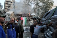 People gather near a damaged site, hauling a destroyed vehicle away, after what Syrian and Iranian media described as an Israeli air strike on Iran's consulate in the Syrian capital Damascus April 1, 2024. REUTERS/Firas Makdesi
