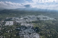 This aerial photograph, taken on October 2, 2023, shows the Rusayo IDP camp, home to tens of thousands of war-displaced people, located at the foot of the active Nyiragongo volcano, on the outskirts of Goma in the East of the Democratic Republic of Congo. Since mid-2022, hundreds of thousands of Congolese have found refuge around Goma after fleeing fighting further north between the Congolese army and the Rwandan-backed M23 rebellion. Every month, over 2,000 women are treated in IDP camps all around the city by Doctors Without Borders (MSF) after being sexually assaulted, mostly by "armed men" while trying to find food in the surrounding forests and fields. (Photo by ALEXIS HUGUET / AFP) (Photo by ALEXIS HUGUET/AFP via Getty Images)
