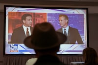 Journalists watch Florida Governor and Republican presidential candidate Ron DeSantis debate California Governor Gavin Newsom on a screen in the media room, in Alpharetta, Georgia, U.S., November 30, 2023. REUTERS/Elijah Nouvelage     TPX IMAGES OF THE DAY
