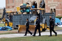 Police officers walk past people operating bulldozers to remove the remnants of a protest encampment in support of Palestinians, that was broken down by police the previous night on the campus of University of California Los Angeles (UCLA), in Los Angeles, California, U.S., May 2, 2024. REUTERS/Carlin Stiehl
