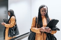 elegant black business woman checking mobile in elevator