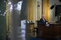 As seen through a window, President Joe Biden addresses the nation on the budget deal that lifts the federal debt limit and averts a U.S. government default, from the Oval Office of the White House in Washington, Friday, June 2, 2023. (AP Photo/Andrew Harnik)