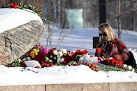 A woman lays flowers for late Russian opposition leader Alexei Navalny at the Solovetsky Stone, a monument to political repression that has become one of the sites of tributes for Navalny, in Moscow on February 19, 2024, following the death of Navalny in an Arctic prison. (Photo by Alexander NEMENOV / AFP) (Photo by ALEXANDER NEMENOV/AFP via Getty Images)