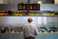 Investors mulling where to park their money have a choice to make: whether to go with a traditional financial adviser or a robotic one. A man watches the financial numbers on the digital ticker tape at the TMX Group in Toronto's financial district, Friday, May 9, 2014. THE CANADIAN PRESS/Darren Calabrese
