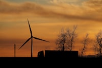 A truck drives in front of a power-generating windmill turbine on the Paris-Lille highway during sunset in Wancourt, France, April 3, 2019. REUTERS/Pascal Rossignol/File Photo