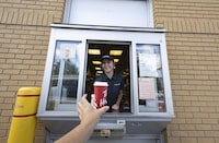 An employee at a Tim Hortons hands out a coffee from their drive-thru window in St-Bruno-de-Montarville, Quebec, September 29, 2022. (Christinne Muschi /The Globe and Mail)