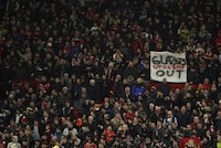 An anti-Glazer family banner is held up by members of the crowd before the English League Cup semifinal second leg soccer match between Manchester United and Nottingham Forest at Old Trafford in Manchester, England, Wednesday, Feb. 1, 2023. The Glazer family are the owners of Manchester United. (AP Photo/Dave Thompson)