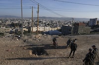 Palestinians inspect the site where a roadside bomb killed one Israeli paramilitary police officer and injured three others during overnight clashes in the Jenin refugee camp, West Bank, on Sunday, Jan. 7, 2024. Six Palestinians and a member of Israel's paramilitary border police were killed in confrontations in a hot spot of violence in the Israeli-occupied West Bank, the Palestinian Health Ministry and the Israeli military said Sunday. (AP Photo/Majdi Mohammed).