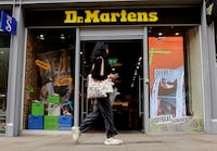 FILE PHOTO: A woman walks past a Dr. Martens store in Manchester, Britain, May 26, 2023. REUTERS/Jason Cairnduff/File Photo
