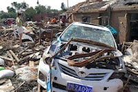 A woman stands on the rubble next to houses and a car damaged by a tornado in Kaiyuan city, in northeastern Chinese province of Liaoning, China July 4, 2019. REUTERS/Stringer ATTENTION EDITORS - THIS IMAGE WAS PROVIDED BY A THIRD PARTY. CHINA OUT.     TPX IMAGES OF THE DAY