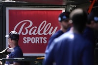 FILE -A Bally Sports sign hangs in a dugout before the start of a spring training baseball game between the St. Louis Cardinals and Houston Astros Thursday, March 2, 2023, in Jupiter, Fla. Comcast has blacked out 15 regional sports networks offered by Bally Sports, escalating a contract dispute with their distributor. The cutoff that began Wednesday, May 1, 2024 affects games played by a dozen Major League Baseball teams based in nine states. (AP Photo/Jeff Roberson, File)